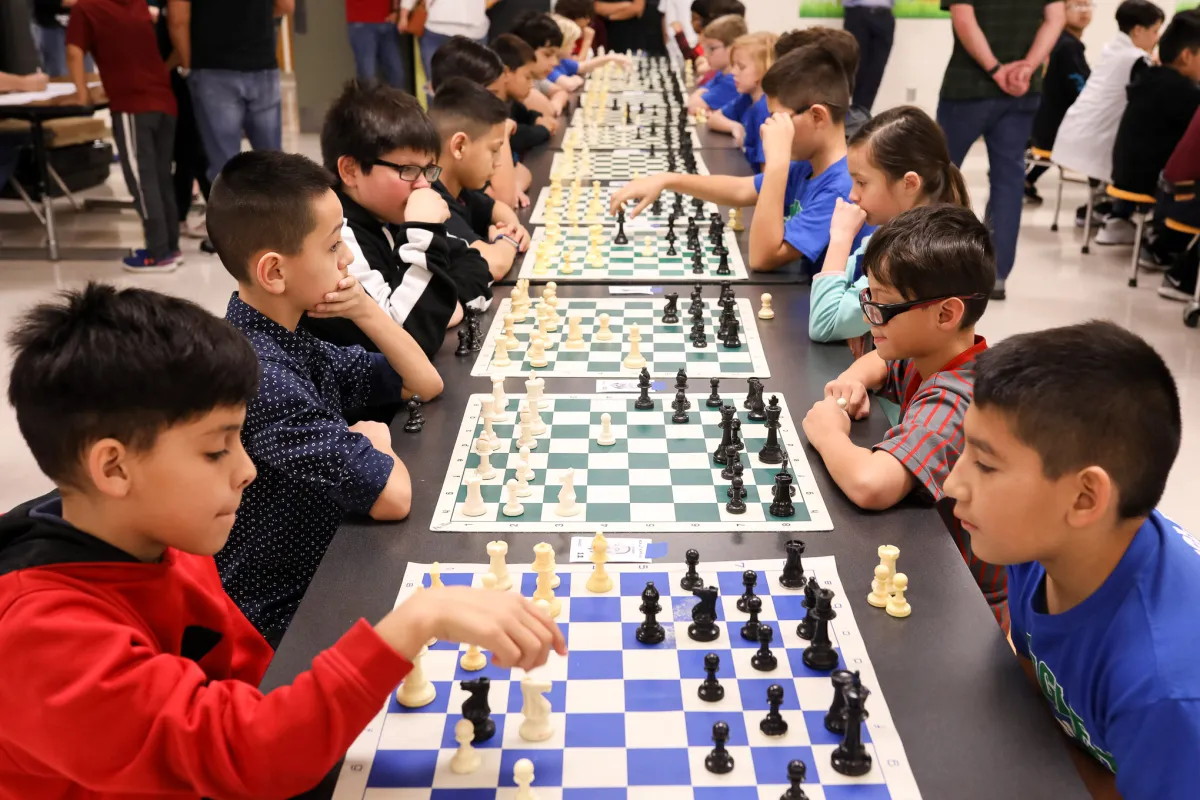 crianças jogando xadrez em um torneio